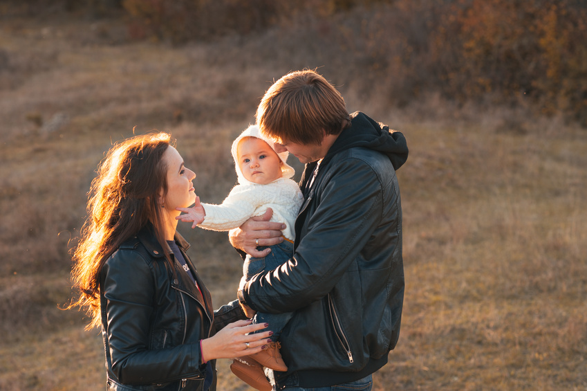 Happy young family having fun outdoors in autumn park.